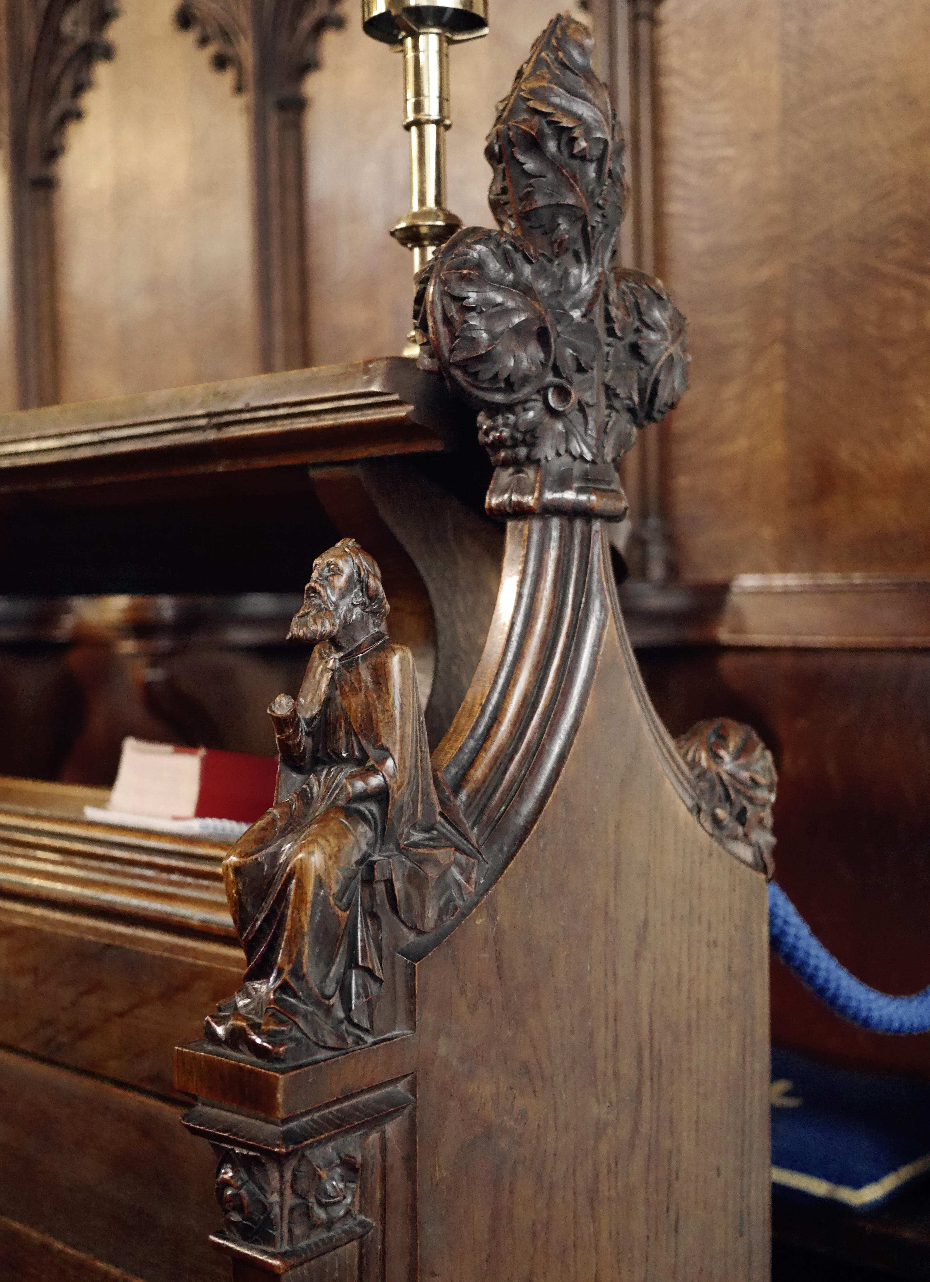 Decorative wooden features of a pew in Great Saint Mary's Church in Cambridge, featuring a carving of an old man and many rosettes